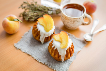 Rom-cakes with peaches and a cup of tea on a sackcloth on wooden background. Breakfast,morning. Top view. Close up. S