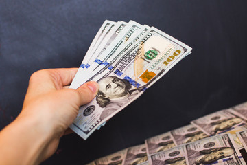 Hand with dollar bills on a black background
