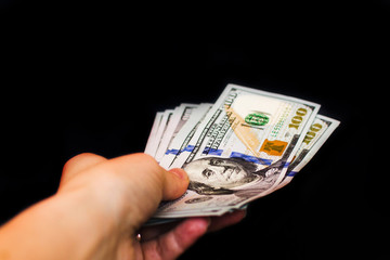 Hand with dollar bills on a black background
