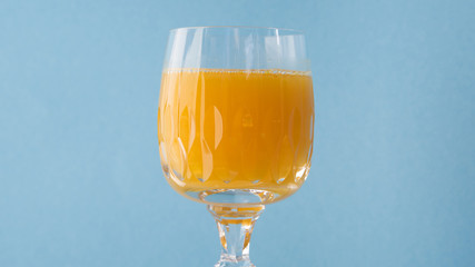 glass of orange juice with blue background.