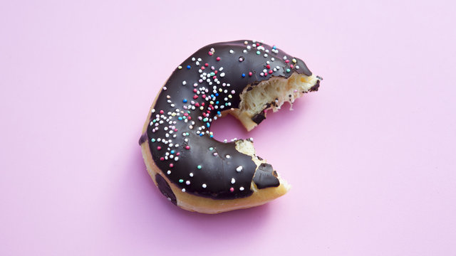 Half Eaten Donut On Pink Table.