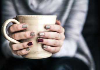 Close-up of a woman's hand holding a cup of hot coffee. fashion, leisure