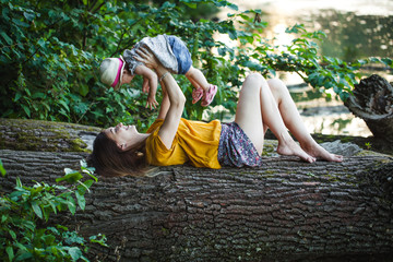 A beautiful mother is playing with her child near a beautiful lake in nature.