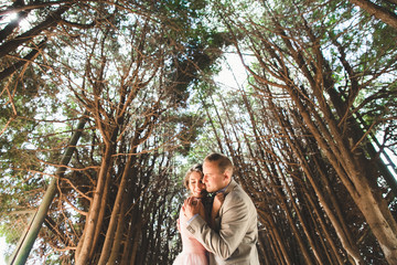 Warm embraces of man and woman standing under tall trees