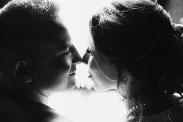 Newlyweds touch each other noses tender sitting before bright window