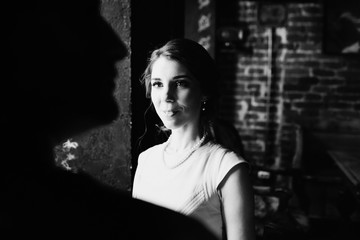 Look from behind groom's shoulder at pretty bride standing before the window