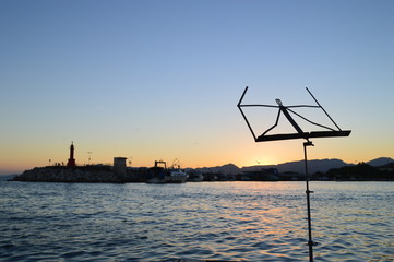 Obraz na płótnie Canvas Accesorios musicales,atril y música en una puesta de sol en el puerto cerca del faro.Cambrils,Spain