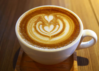 A cup of latte coffee with love heart and flower pattern.