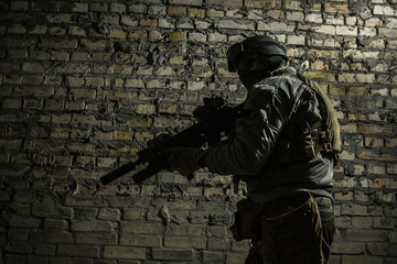 Special forces operator pointing weapon in the dark. Combat helmet, and bulletproof vest are on. Low key image, shadow soldier