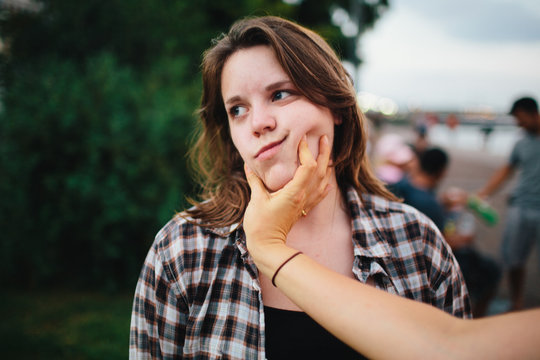 Friends squish the face of a young caucasion woman