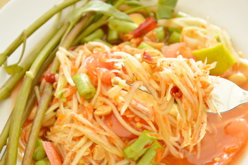 Somtum Thai green papaya salad tasted spicy sour and sweet on fork