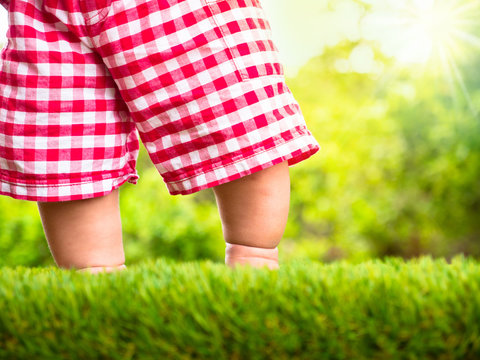 Baby standing on green grass with sunlight