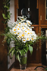 Vase with daisies stands on wooden wardrobe