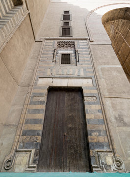 Wooden aged wall, wooden door and striped black and white marble decorations, Mosque of Sultan Hasan, Medieval Cairo, Egypt