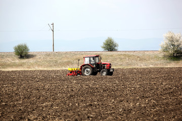 Obraz premium Farmer in tractor preparing land with seedbed cultivator.