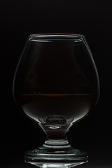 A glass of cognac on a black background