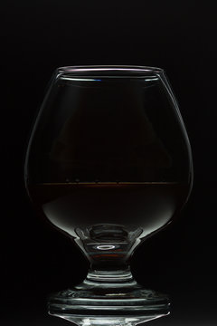 A glass of cognac on a black background