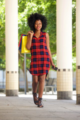 African woman walking with shopping bags and mobile phone