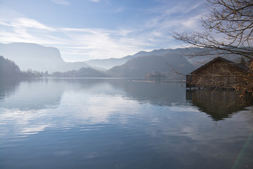 wonderful landscape winter scenery with wooden house floating on lake bled surrounded by julian...