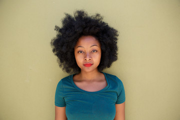 beautiful serious young black woman standing by wall
