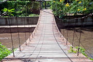 Wire hanging bridge with wooden pathway in Thailand.