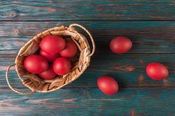 Easter concept with red eggs in basket over old wooden background