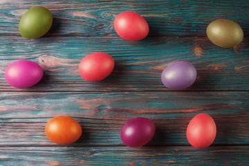 Obraz premium Flat lay of multicolored Easter eggs over old wooden background
