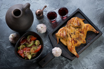 Georgian traditional tapaka chicken with red wine and vegetable salad, high angle view, studio shot