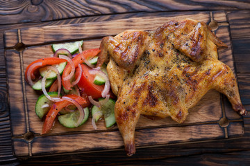 Close-up of a wooden serving tray with chicken tabaka, georgian traditional dish, elevated view