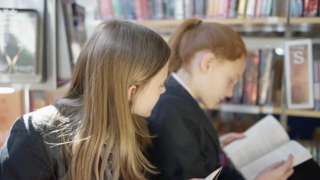  Young students reading books & chatting in school library