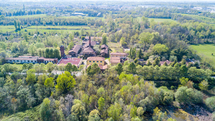 Obraz premium Natura e paesaggio: vista aerea di una fornace e ciminiera, bosco e di laghi, verde ed alberi. Parco delle Groane, Mombello (Laghettone), Limbiate, Milano, Italia