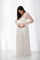 Smiling Pregnant Woman in a White Lace Gown