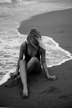 Woman sitting at the edge of water on seashore