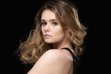 Beauty in motion. Horizontal studio shot of an attractive curly haired woman posing on black background at the studio