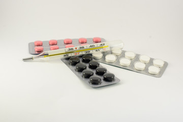Different medicines. Tablets, pills in blister pack. Medications drugs and thermometer on a white background