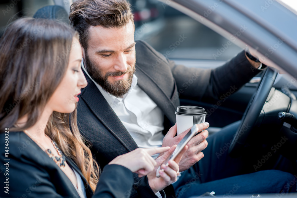 Wall mural business couple having a conversation while driving a car in the city