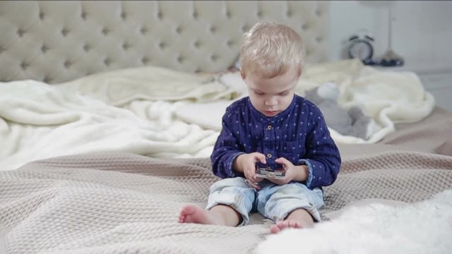 Toddler is using a smartphone on a bad. FULL HD slow motion