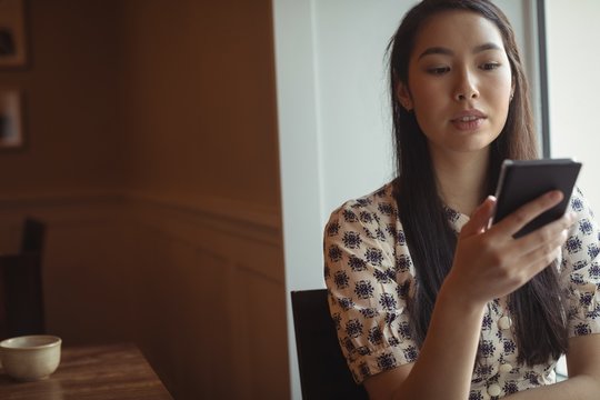 Woman using mobile phone near window