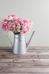 pink persian buttercup flowers. Curly peony ranunculus in Metallic gray vintage watering can, copy space.