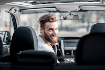 Portrait of a handsome bearded man looking back sitting on the front seat of the car