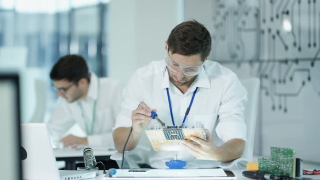  Electronics engineers working in lab building & testing electronic devices