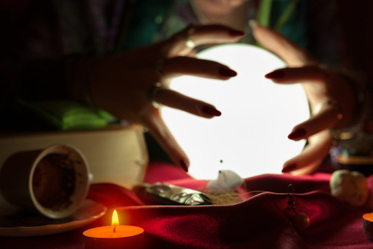 Hands of fortune teller woman around crystal ball