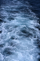 Fototapeta na wymiar Wake, trace or trail with waves and foam in sea