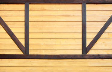 Part of the wall of the building is trimmed with a decorative board of light color with inserts from a bar of dark wood
