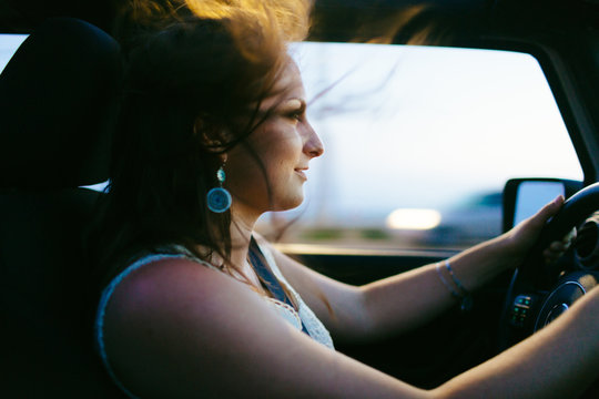 20-something female drives jeep with hair blowing at sunset on Pacific Coast Highway, California