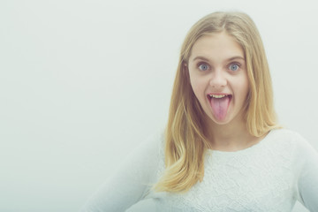 Pretty happy young girl with blond hair showing tongue