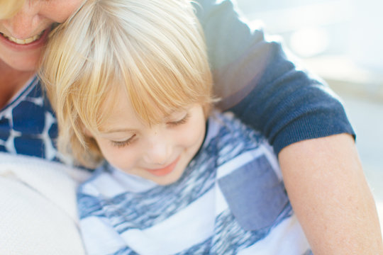 4 year old boy smiles while laying in mother's arms