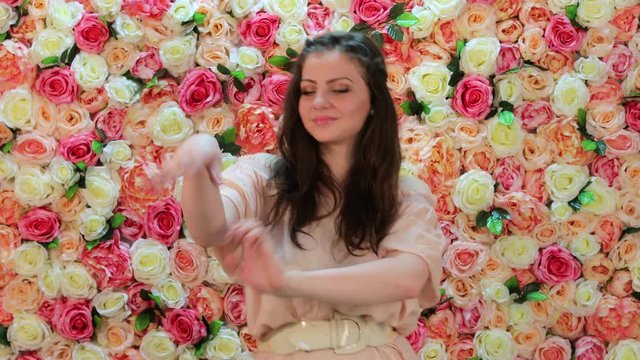 Portrait of young beautiful brunette dancer girl, closeup on a background of bright floral wall