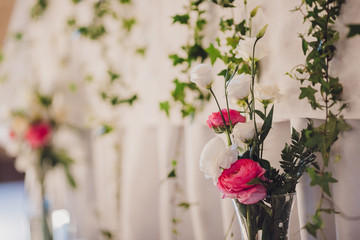 The vases with flowers standing near wedding table