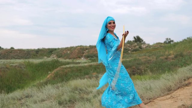 Oriental beauty Sa'idi dance. Nice girl wearing a national costume dancing shepherdess with shepherd's cane outdoors. Nomads.